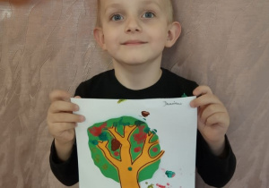 Chłopiec pokazuje swoje jesienne drzewo.