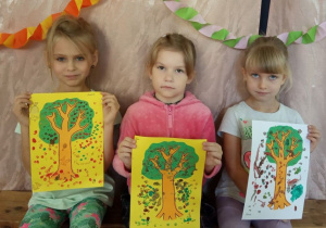 Dziewczynki pokazują swoje jesienne drzewa.