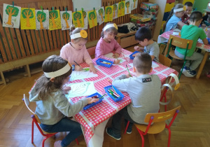 Dzieci rysują kredkami przy stolikach