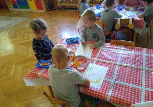 Dzieci rysują kredkami przy stolikach