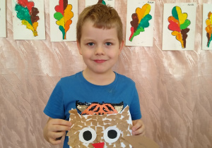 Chłopiec prezentuje swoją pracę - sowa wykonana wydzieranką