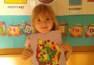 Dziewczynka prezentuje swoją pracę, liść wyklejony wydzieranką z kolorowego