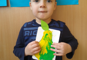 Chłopiec prezentuje swoją pracę- wyklejona plasteliną gruszkę