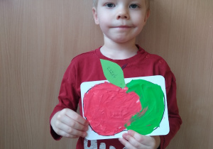 Chłopiec prezentuje swoją pracę- wyklejone plasteliną jabłko