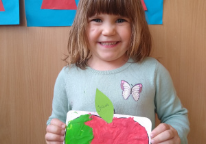 Dziewczynka prezentuje swoją pracę- wyklejone plasteliną jabłko