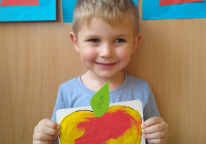 Chłopiec prezentuje swoją pracę- wyklejone plasteliną jabłko