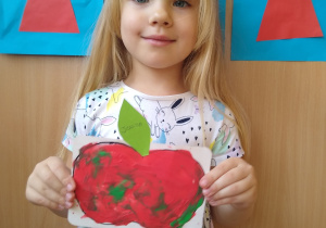 Dziewczynka prezentuje swoją pracę- wyklejone plasteliną jabłko