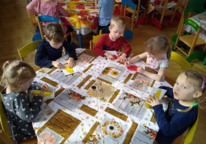 Dzieci przy stolikach plasteliną wyklejają kontury gruszki i jabłka