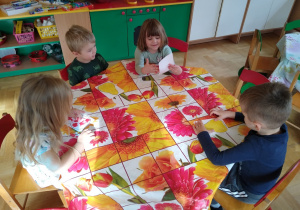 Dzieci przy stolikach plasteliną wyklejają kontury gruszki i jabłka
