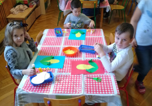 Dzieci przy stolikach naklejają kukurydzę z zielonego i żółtego papieru